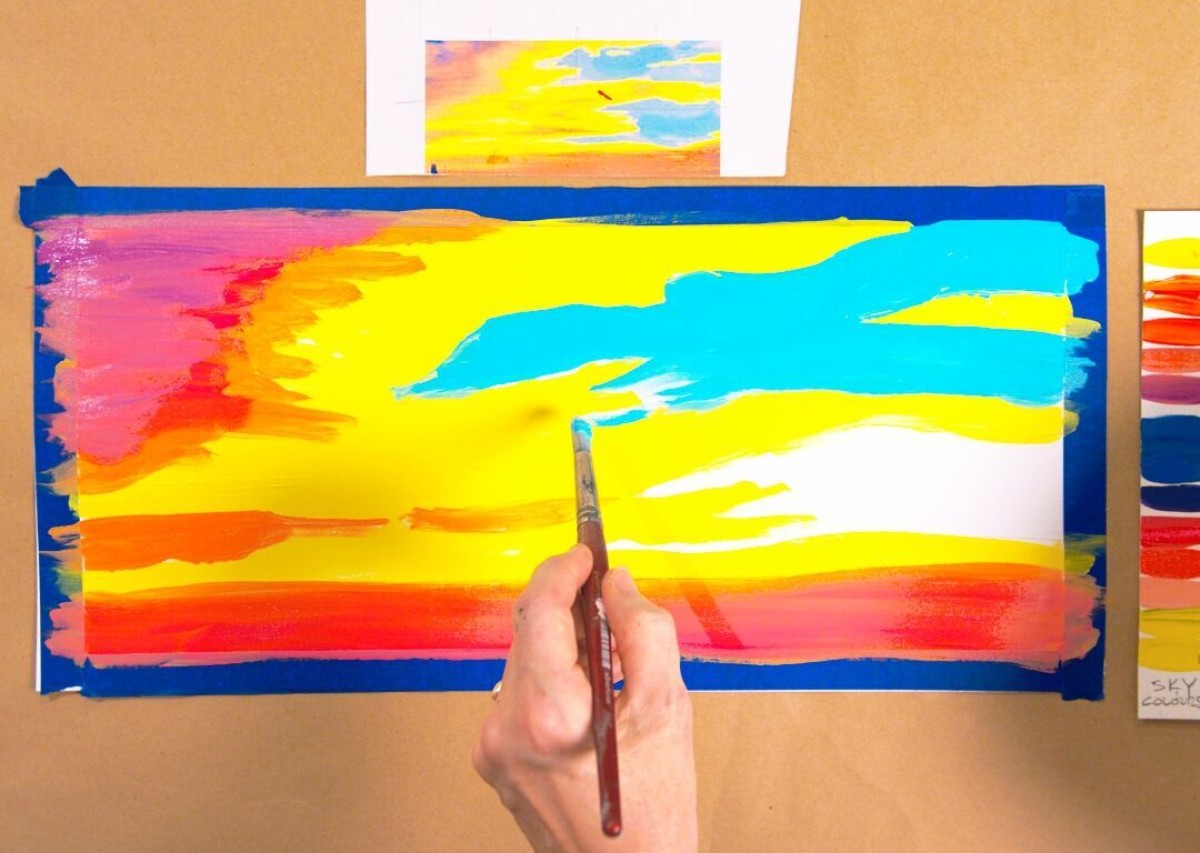 A hand hovers over a half painted piece of paper