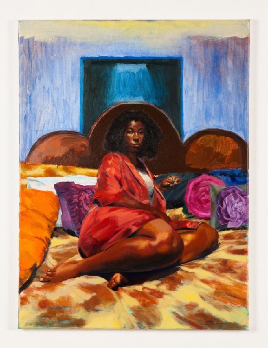 A Black woman dressed in red sits on top of colorful pillows and blankets