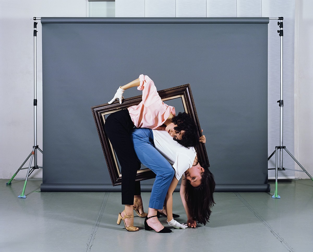 Photograph of two women inside a picture frame, against a professional backdrop