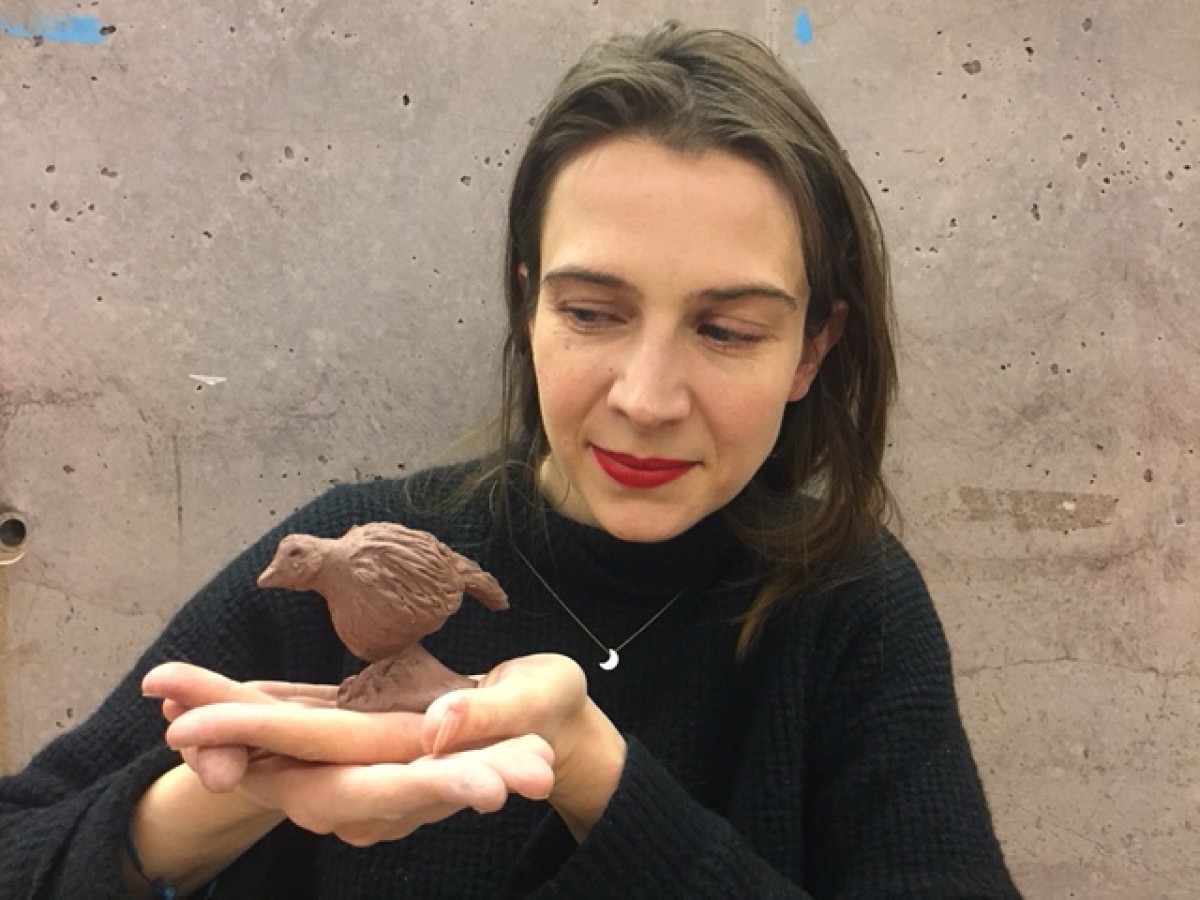 A woman holding a clay bird sculpture