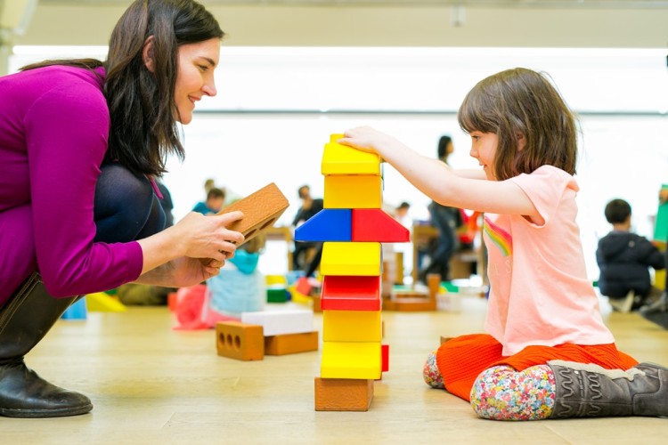 Mother and daughter build a structure with multi-coloured bricks.