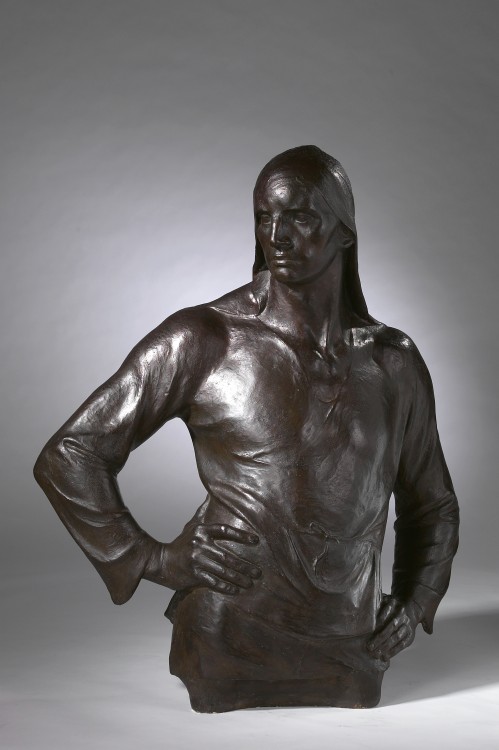 A bronze sculpture depicting the torso and head of man, standing in a jaunty pose.