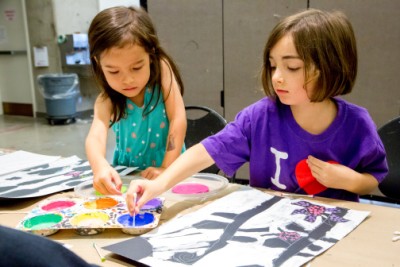 Two children reach for paint while taking an art-making class at the AGO