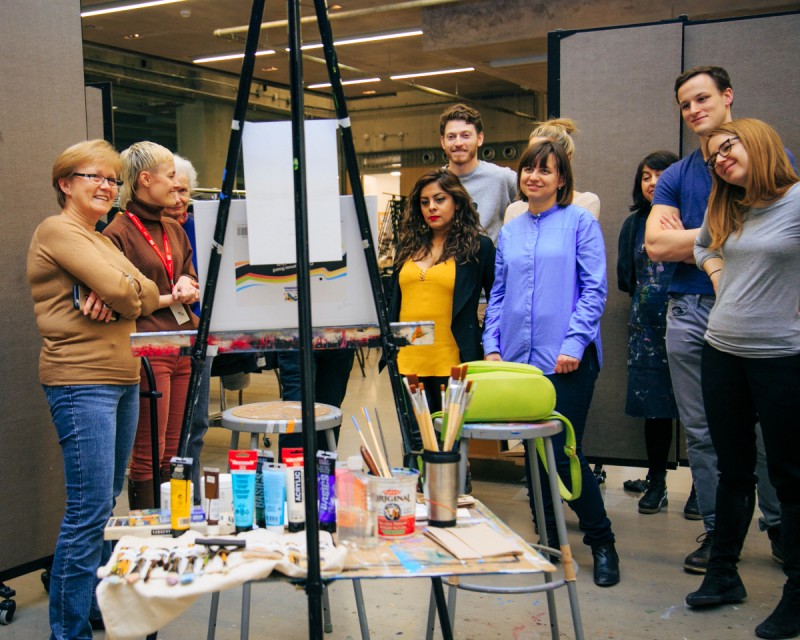 students in art class looking and painting on easel