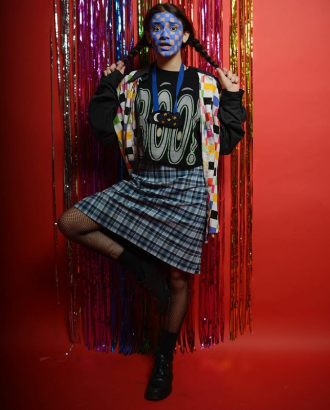 youth with painted face standing in front of tinsel curtain