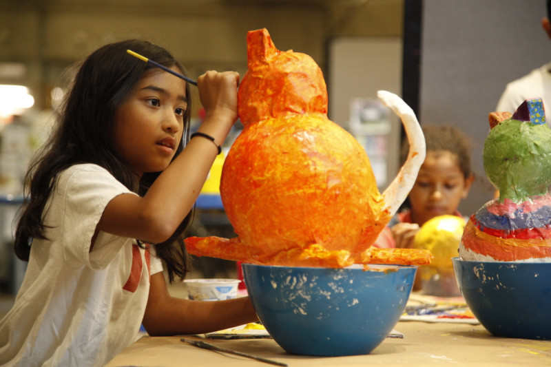 child painting papier mache sculpture