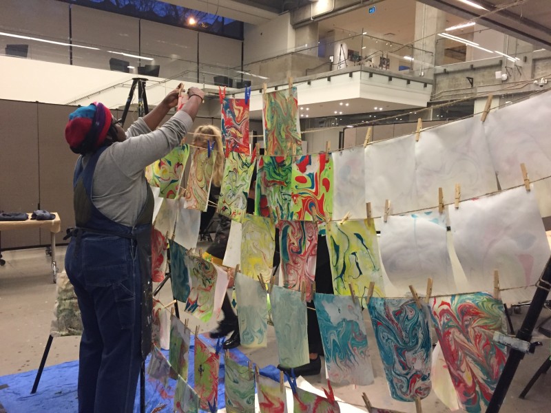 instructor hanging paper marbling projects on clothesline to dry