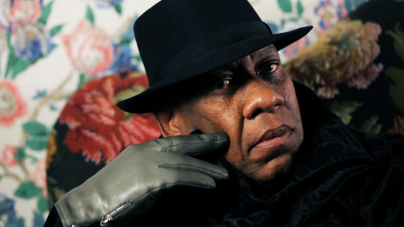 image of Andre Leon Talley in a hat in front of floral wallpaper