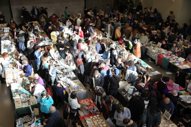 overhead photo of canzine festival with vendors selling printed materials at long tables