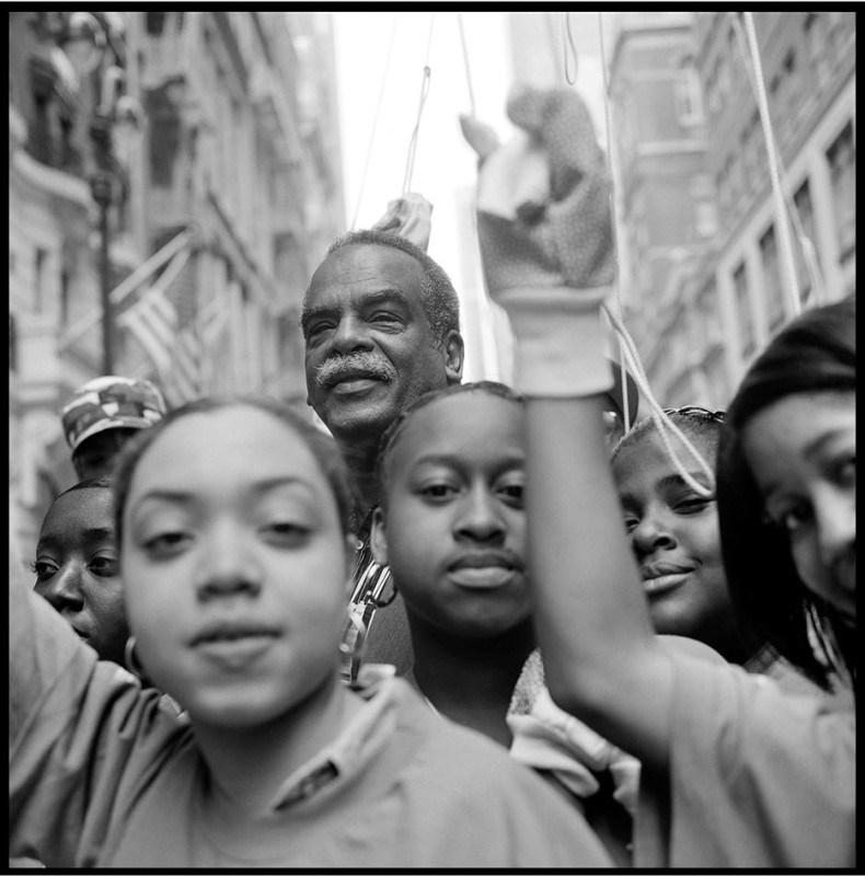 black and white photo of writer Edouard Glissant on a city street with young people in foreground