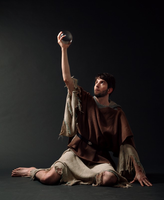 Composer Owen Pallett in rustic tunic holding a crytal orb