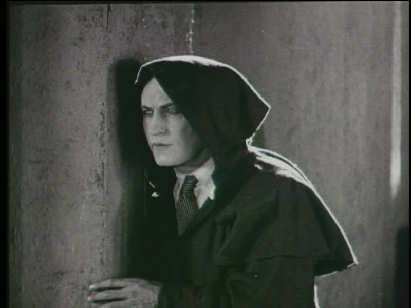 Harry Houdini as Heath Haldane in a black hooded cape in a still from the film 