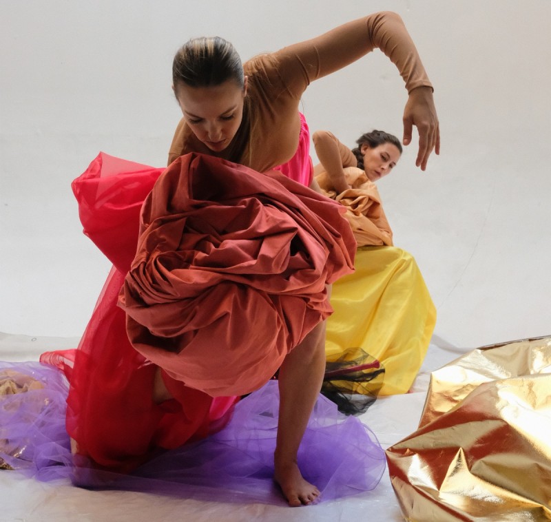 Image of two dancers wrapped in brightly colored cloth. 