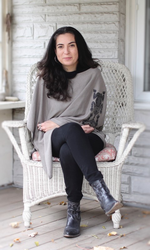 Writer and Journalist Tanya Talaga sitting on a white-painted porch in a white wicker chair