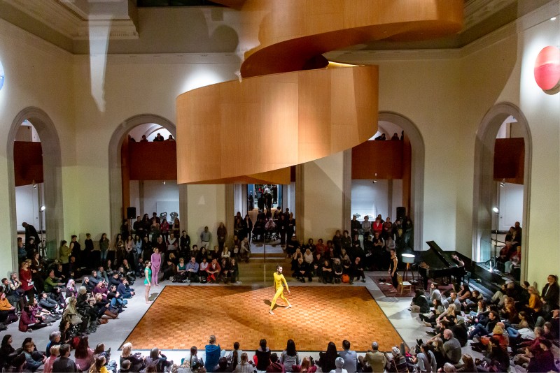 AGO's Walker Court full of people, a square dance floor centred under the spiral stairs, featuring a dancer in a yellow unitard