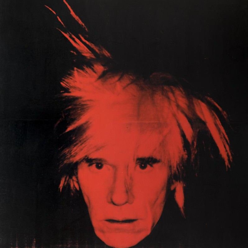 self portrait of artist Andy Warhol, closely cropped to his head and hair, which is red against a black background. His hair goes upward at different angles. 