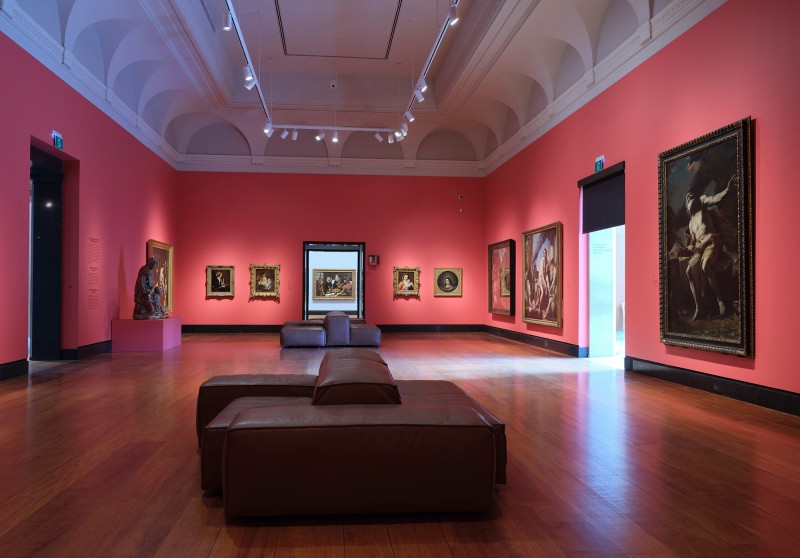 classic gallery setting with red walls, wood floors and master artworks