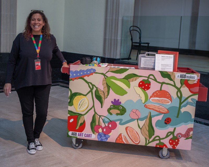 Smiling woman standing beside colourful Art Cart