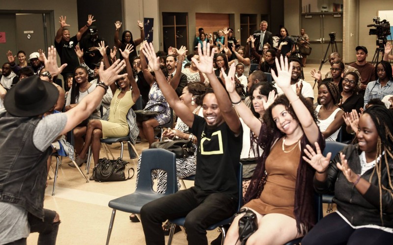 A group of people sitting and smiling with their hands in the air