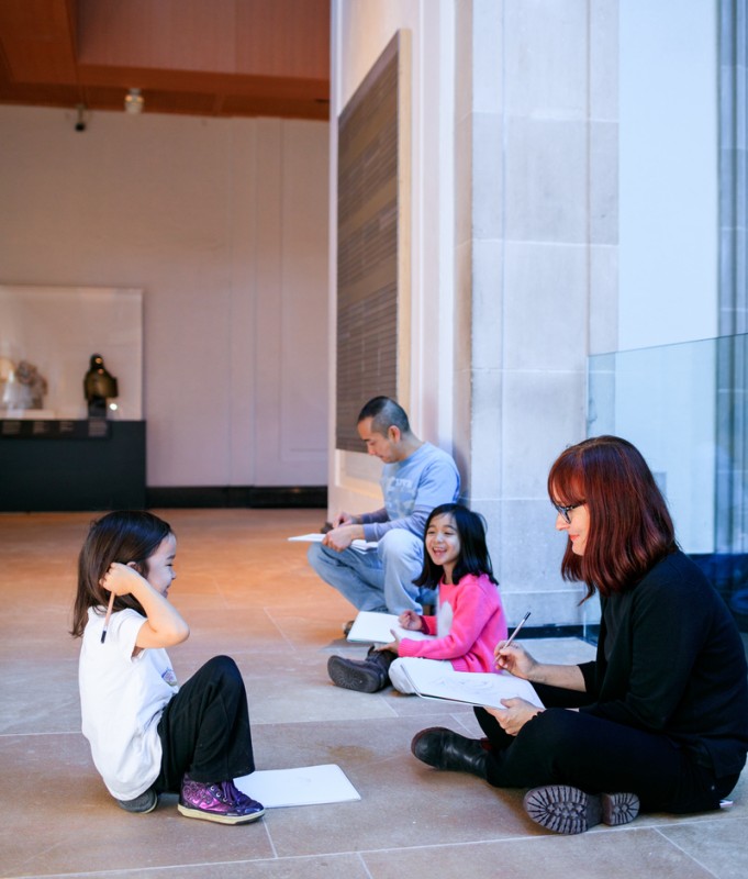 Two adults and two children sitting on the ground with art books