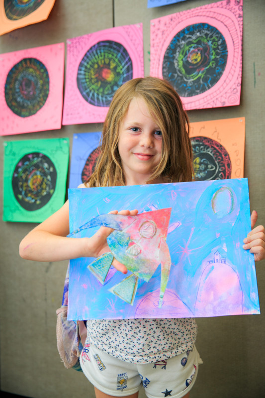 child holding colourful artwork during rainbow adventures camp