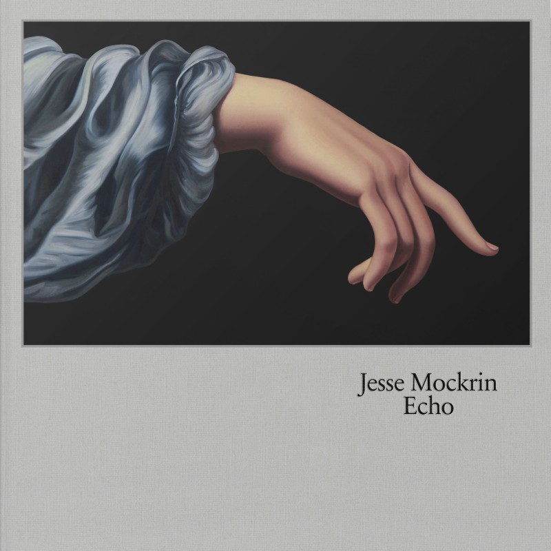 The book cover for Jesse Mockrin: Echo. It features a hyperrealist painting of a delicately poised hand draped in a flowing, bluish fabric against a black background. 