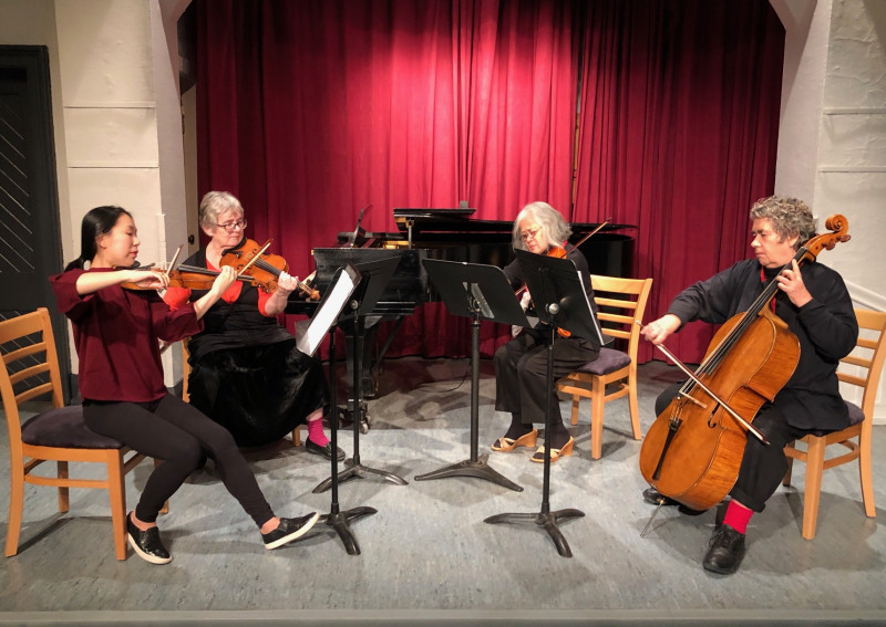 Four women playing music in a quarter