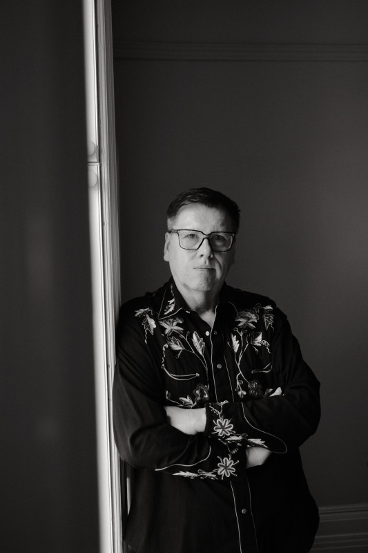 Black and white photo of a man leaning against a wall