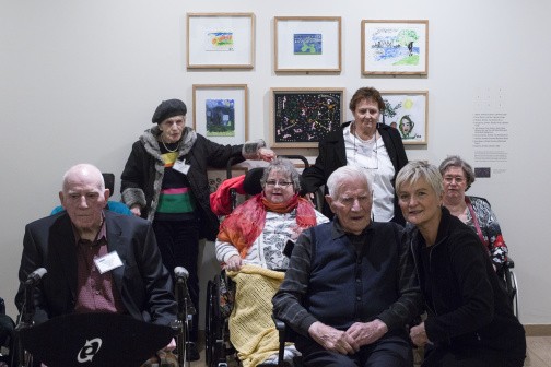 visitors in wheelchairs with caregivers in front of art works