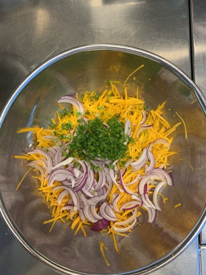 grated pumpkin in bowl with sliced onions and chilis